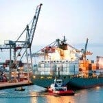 cargo ship maneuvered by tugboats